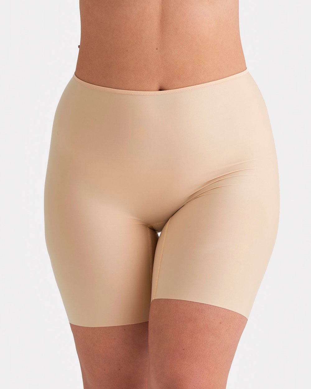 A person wearing seamless nude-colored shapewear shorts, standing against a plain white background.