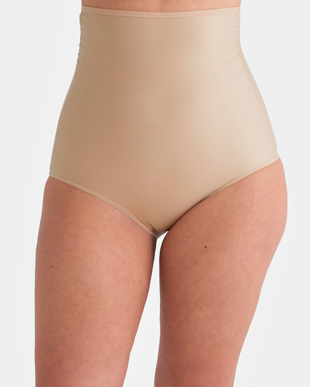 Person wearing high-waisted, beige shapewear against a white background, showcasing a smooth and seamless fit.