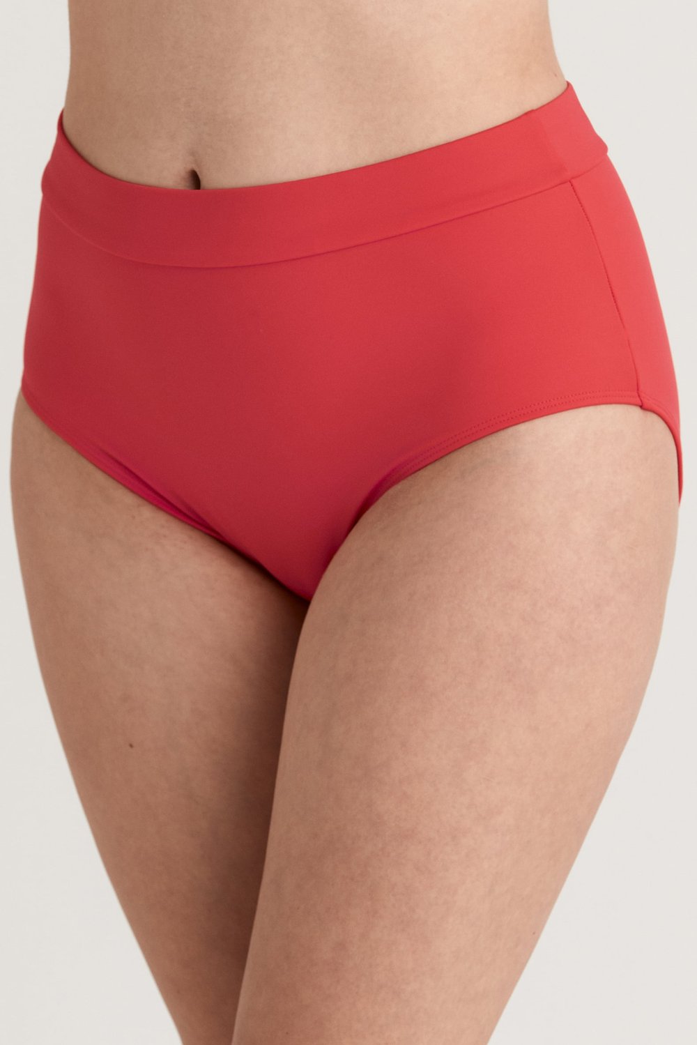 Lähikuva naisesta, jolla on yllään Miss Maryn korkeavyötäröinen, koraalinpunainen Maya-maxi-bikinialaosa.