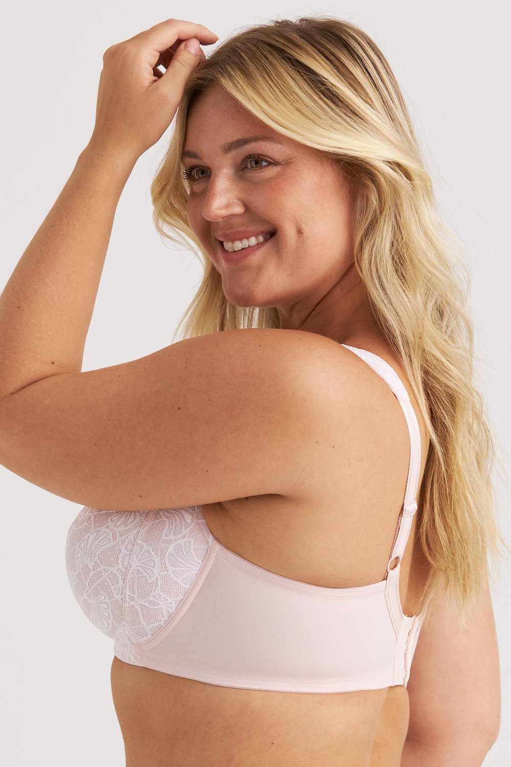 Side view of a smiling woman wearing the dusty pink Lace Illusion underwired bra by Miss Mary.