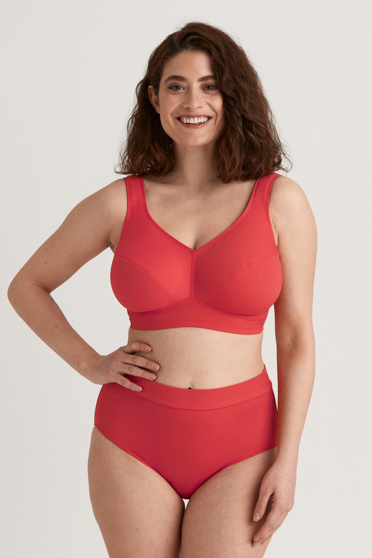 Hymyilevä nainen, jolla on yllään Miss Maryn korallinvärinen Maya-maxi-bikinialaosa ja yhteensopiva bikinyläosa.