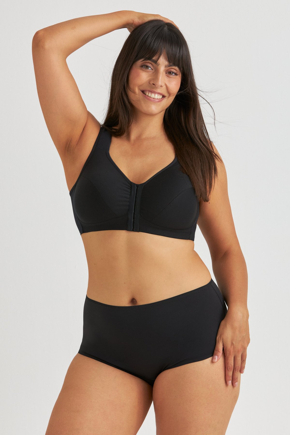 Femme souriante portant le soutien-gorge sans armatures en coton noir Miss Mary à maintien postural et fermeture devant.