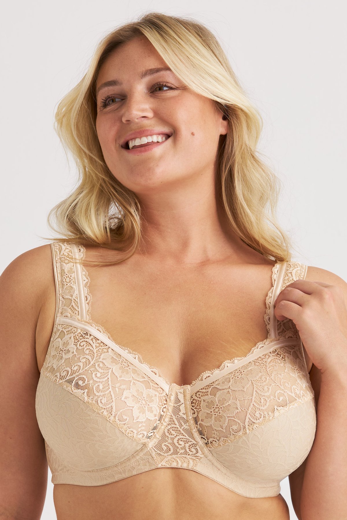 Femme souriante portant le soutien-gorge avec armatures beige Floral Jacquard Miss Mary aux bonnets en dentelle extensible.