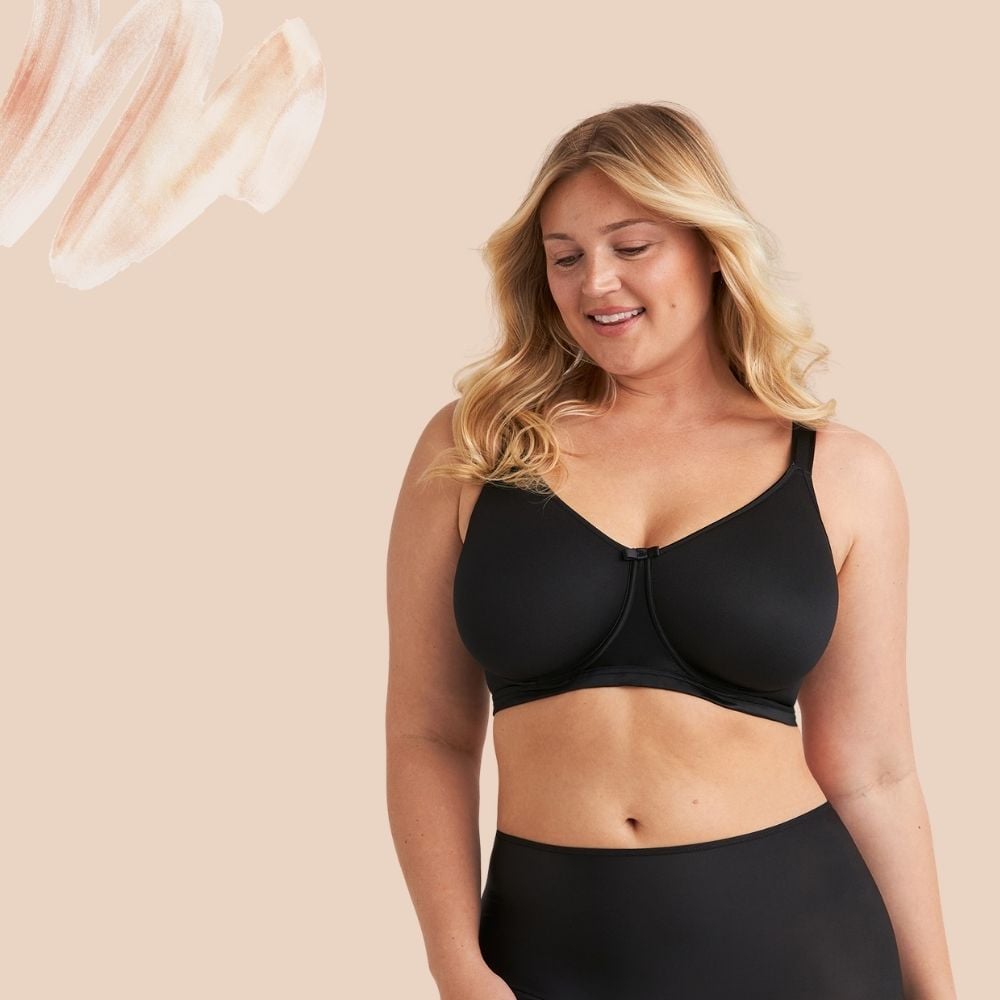 A smiling woman with blonde hair wearing a black bra against a beige background with abstract brushstrokes.