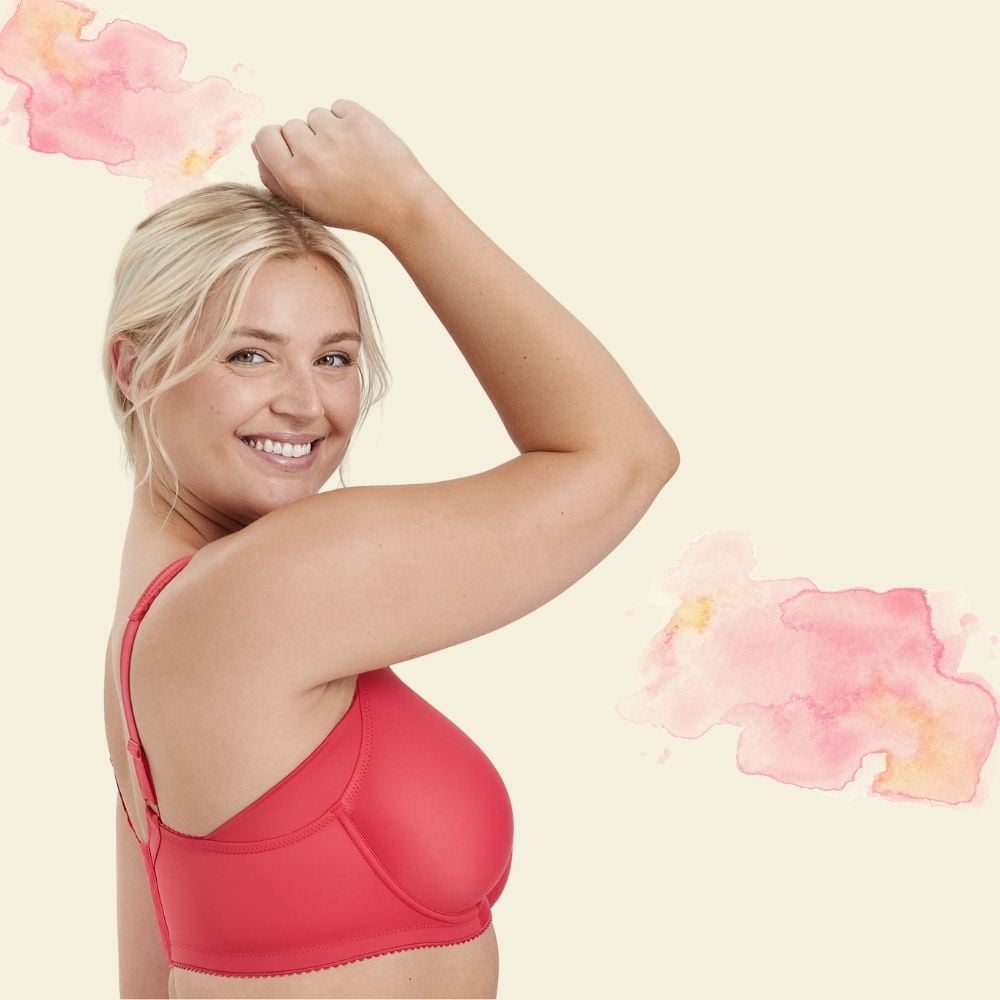 Smiling person with blonde hair wearing a red bra against a beige background with pink watercolor accents.