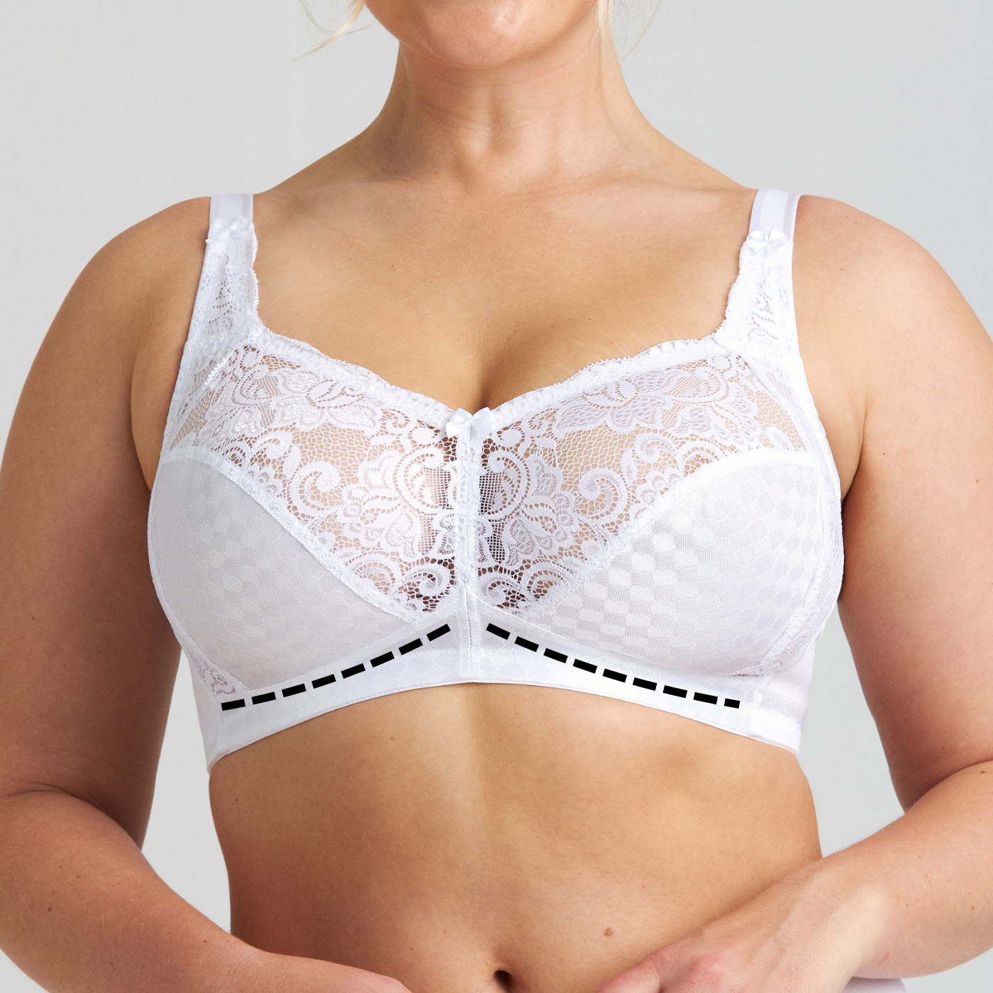 Close-up of a woman's torso wearing a white lace full-coverage bra with patterned cups and a small center bow.
