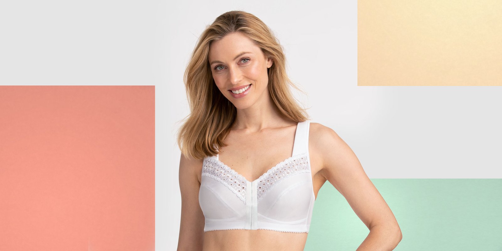 Smiling woman wearing a white lace bra, standing against a colorful geometric background.